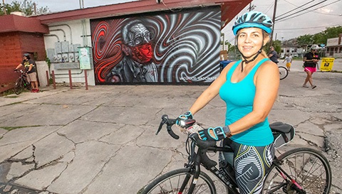 Cyclist in front of a COVID-19 mural of a man with a mask